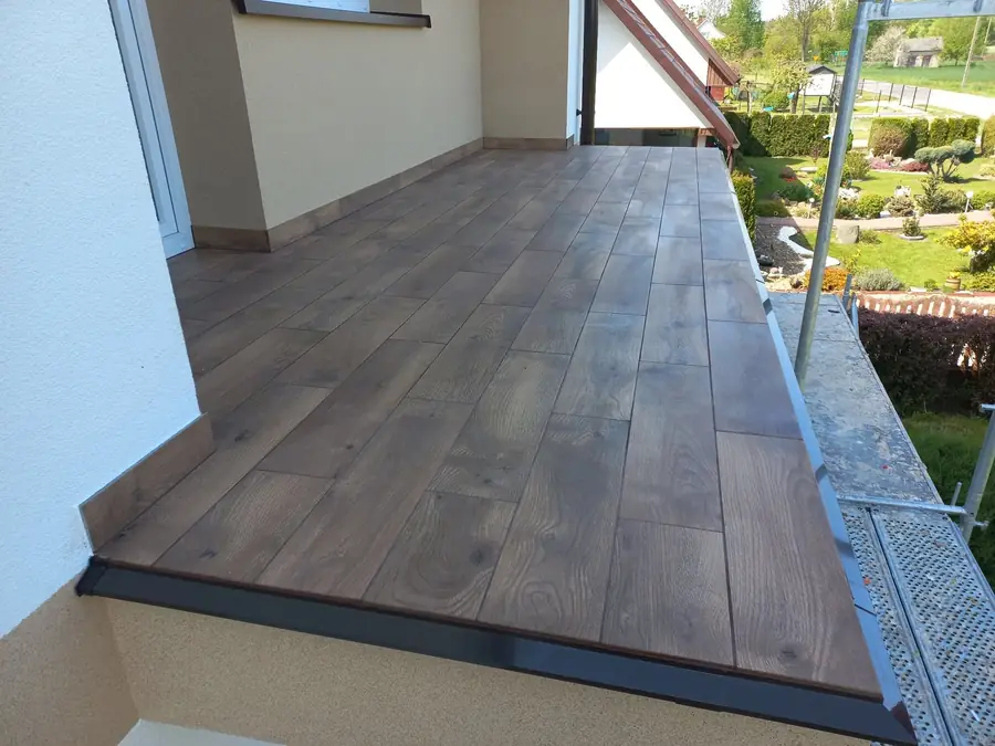 Balkon wyłożony płytkami w kolorze drewna, z obróbką krawędzi