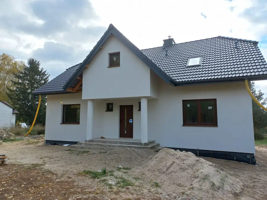 Nowy dom z białą elewacją, kolumnami przy wejściu i szarym dachem
